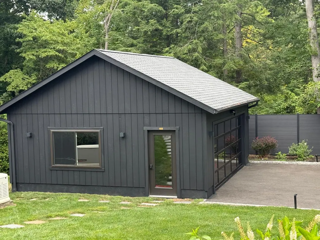Detached studio building with black painted siding on a green lawn