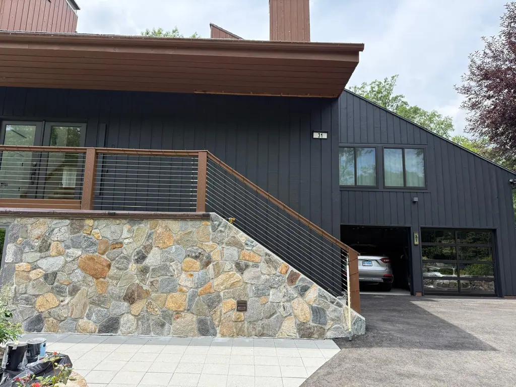 Black painted siding above a stone wall and exterior staircase