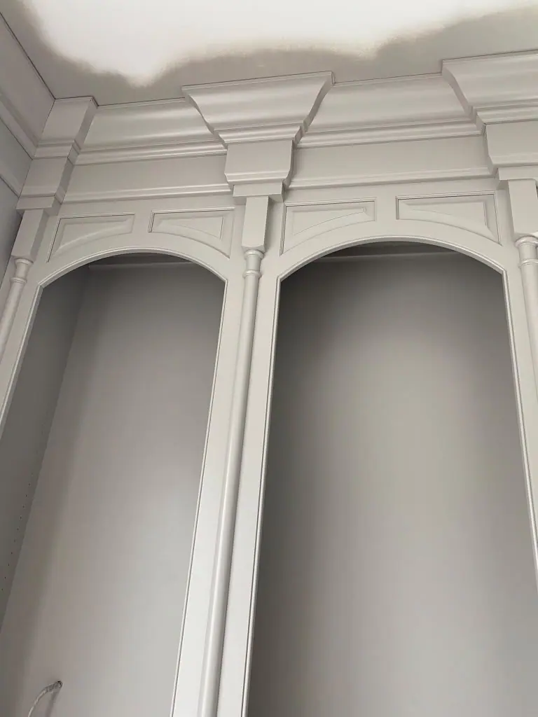 Close view of arched bookcase tops and crown detail painted gray