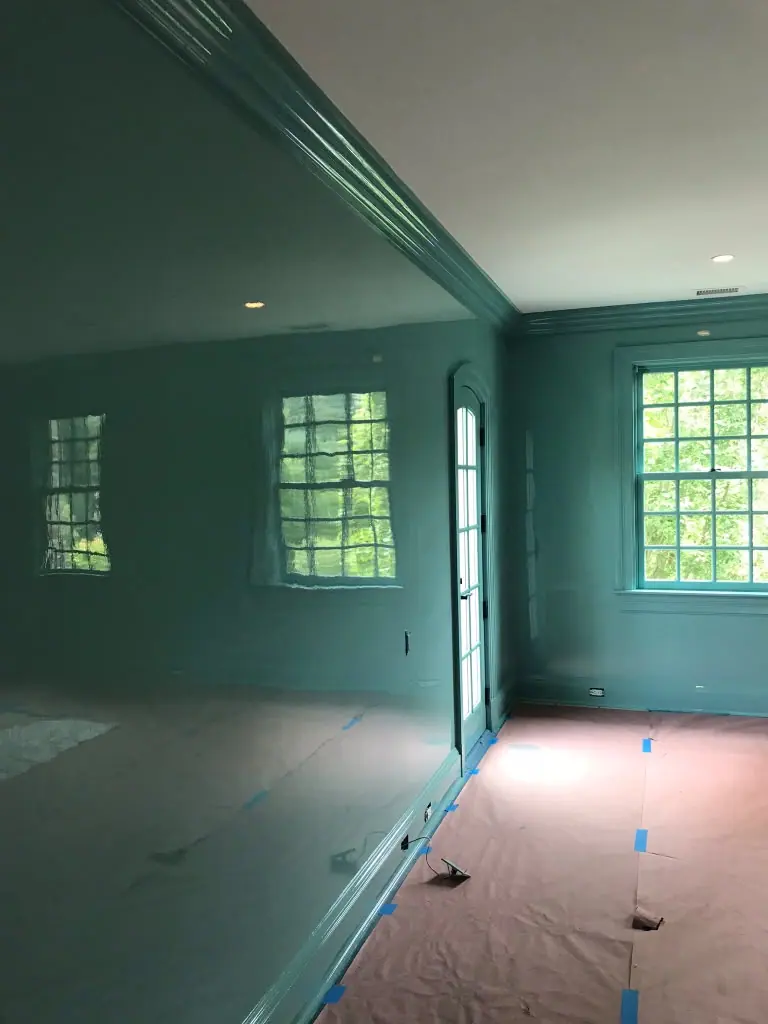 Living room with high-gloss teal walls, crown molding and paneled corner