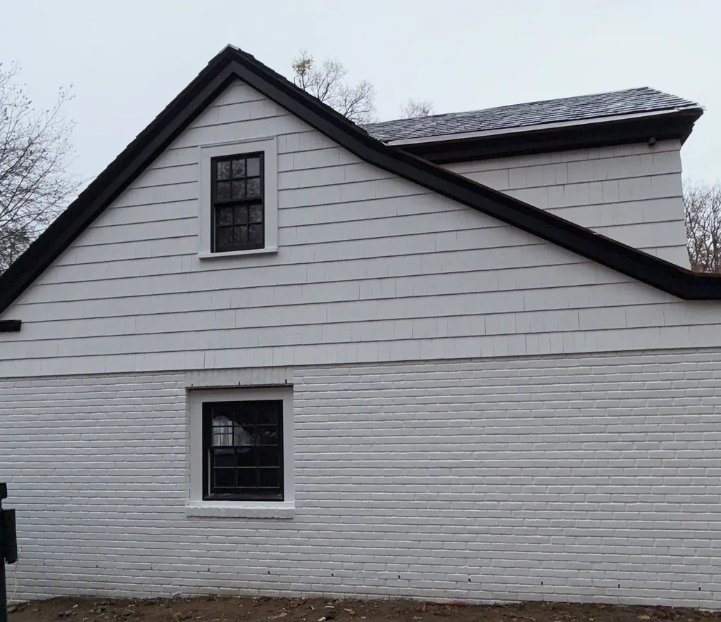 Painted white brick and siding on a gable end with black windows
